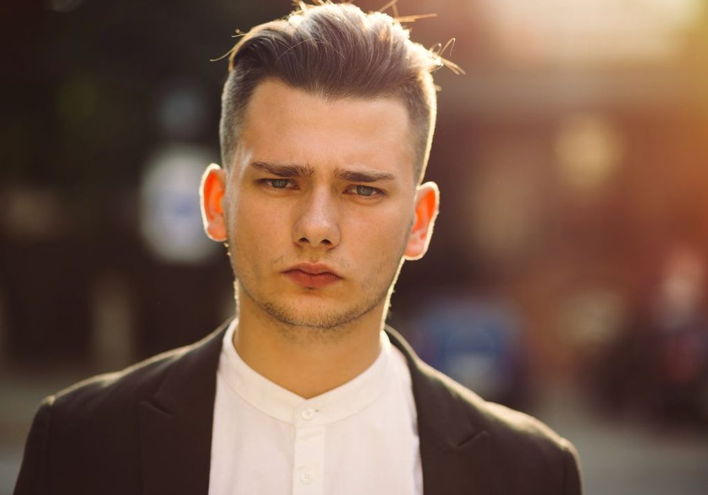 Man with a round face wearing a high skin fade with a swept-up quiff on top